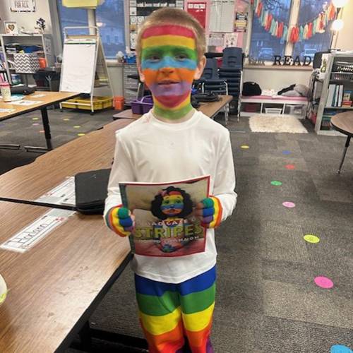 A student holds his favorite book while dressed exactly like the book's main character.